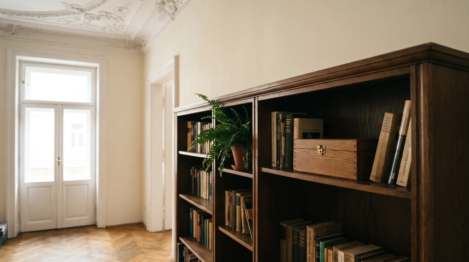 KI-generiertes Bild: Ein helles Altbau-Wohnzimmer mit Flügeltüren und einem Bücherregal, zwischen den Büchern steht ein kleines Holzobjekt in Buchformat.